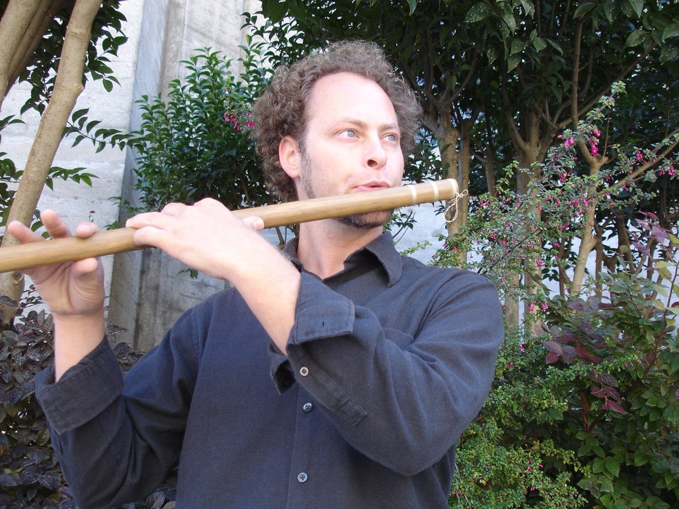 Aharon playing the bansuri, a North Indian bamboo flute, in a garden