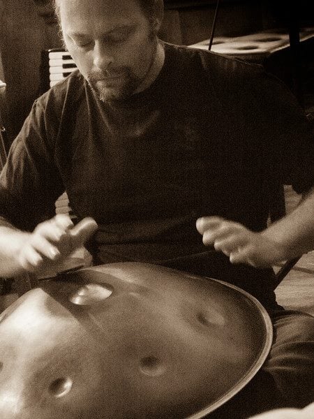 Aharon Wheels Bolsta playing the handpan, photographed in warm sepia tones