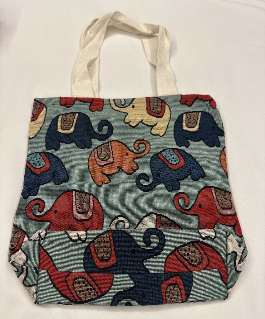 The sage-green elephant tote laid flat, handles folded down, showing the front panel and the deep fold across the lower third