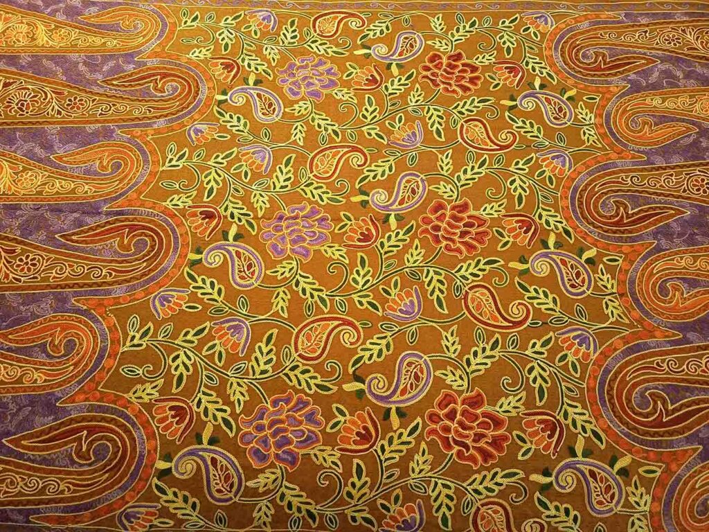 Close view of the ochre field: a cream vine with red and purple flowers between the large purple paisley shapes that frame it on both sides