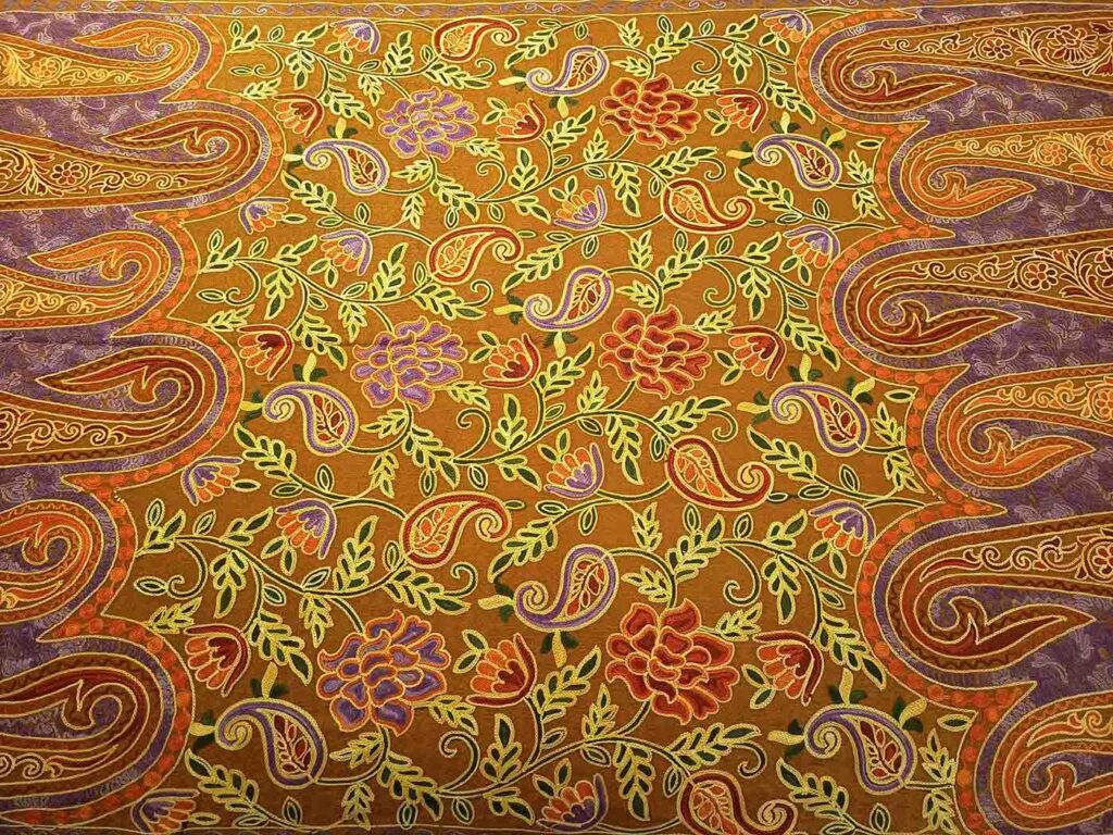 The same ochre floral field at a wider angle, the purple paisley borders curling in from the left and right edges