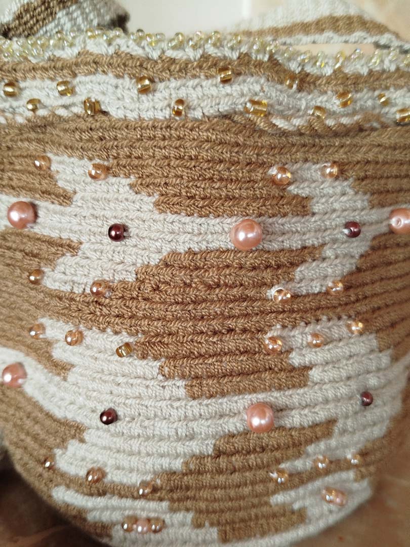 Brown-and-beige crocheted Wayuu mochila bag with a tan geometric pattern, gold bead trim and twin tassels on the drawstring